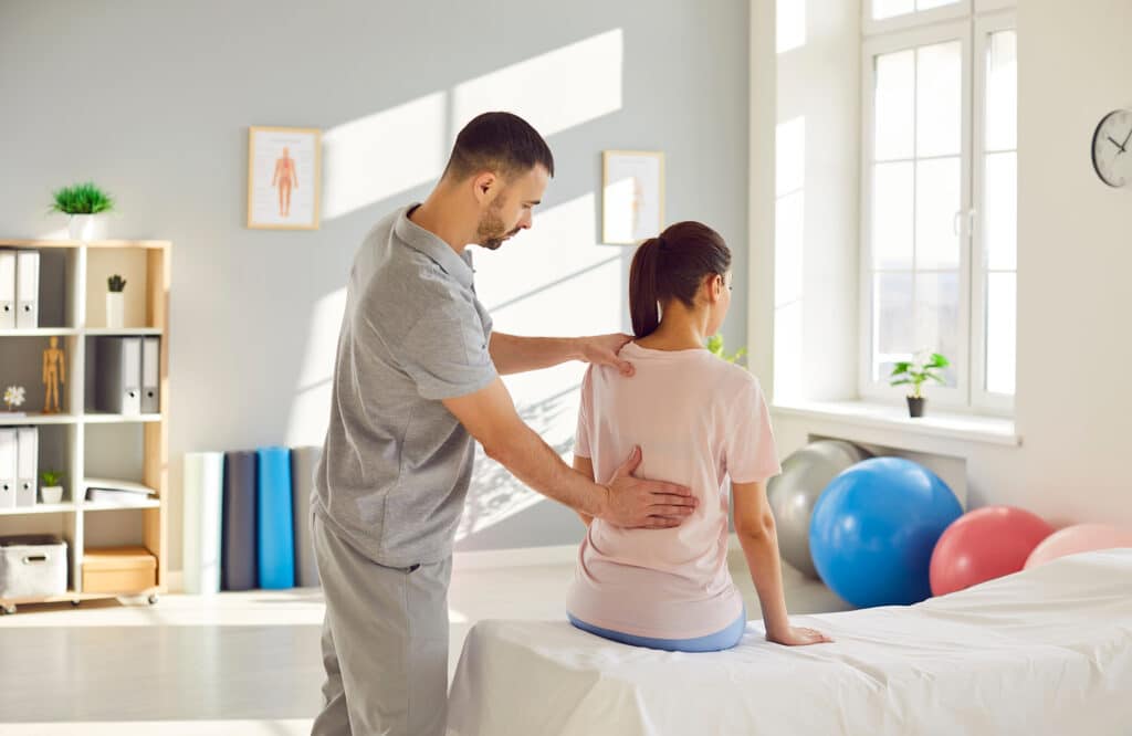 Post traumatic rehabilitation, female back spine massage, physical therapy by professional male nurse, manual chiropractor, physical therapist doctor to help with trauma, lower back pain reducing