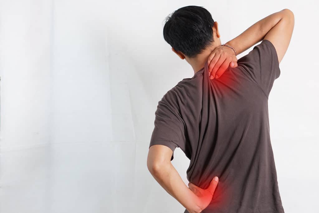 A man displaying signs of back and neck pain
