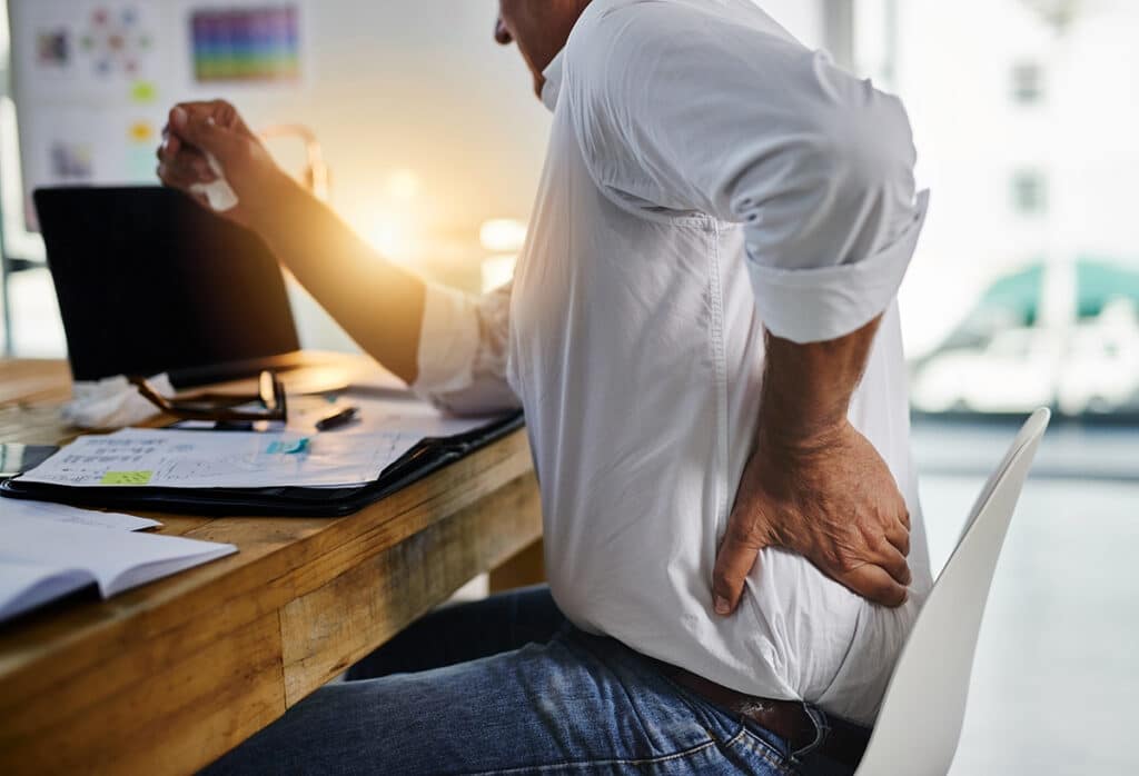 A man suffering from back pain while sitting