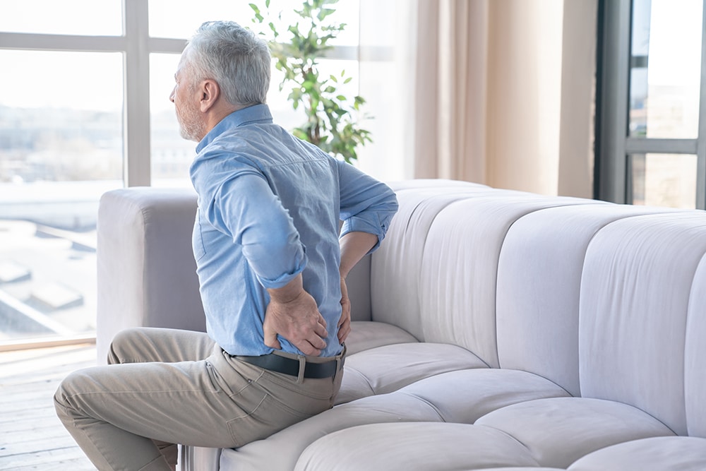 A man struggling with back pain and considering specialist care