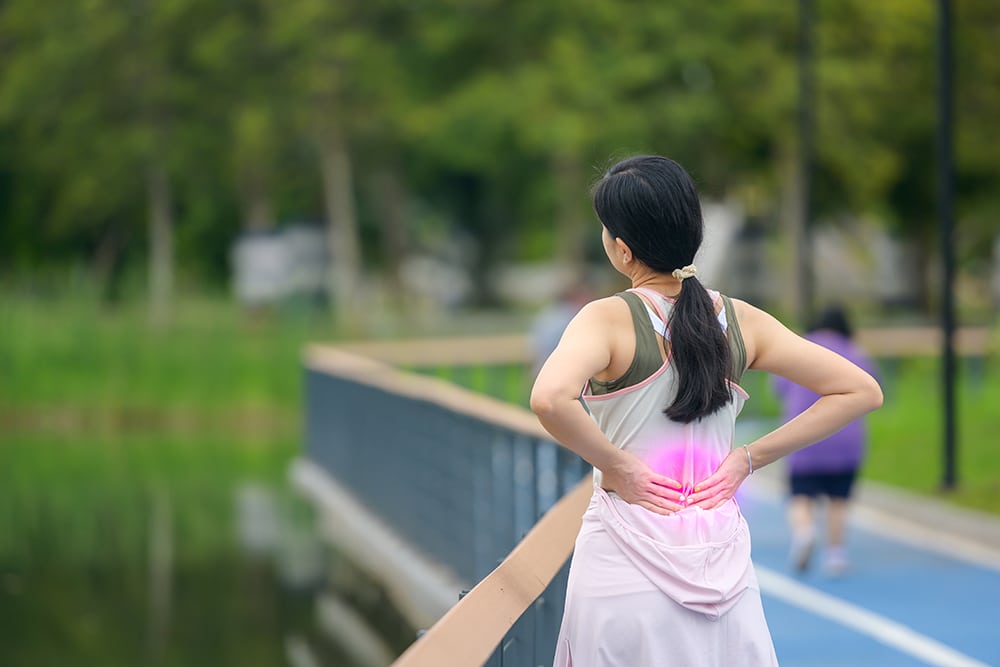 A woman experiencing back pain while walking