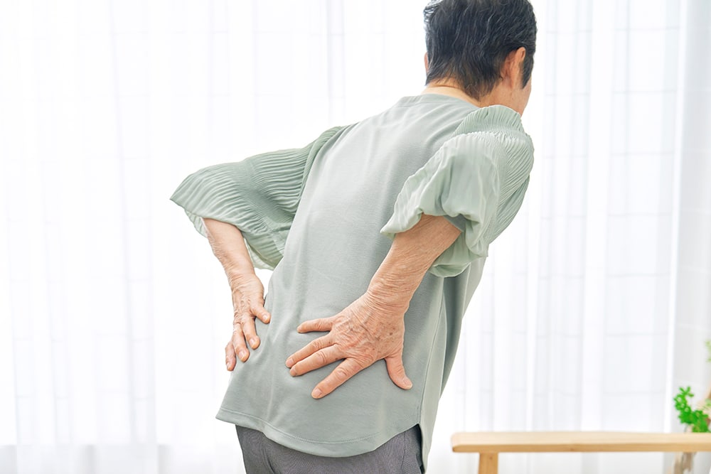 Woman holding her lower back while experiencing discomfort caused by a slipped disc.