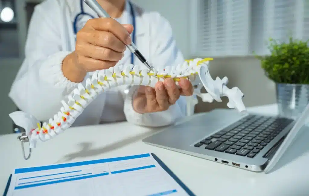 Doctor assessing herniated disc recovery using spine model