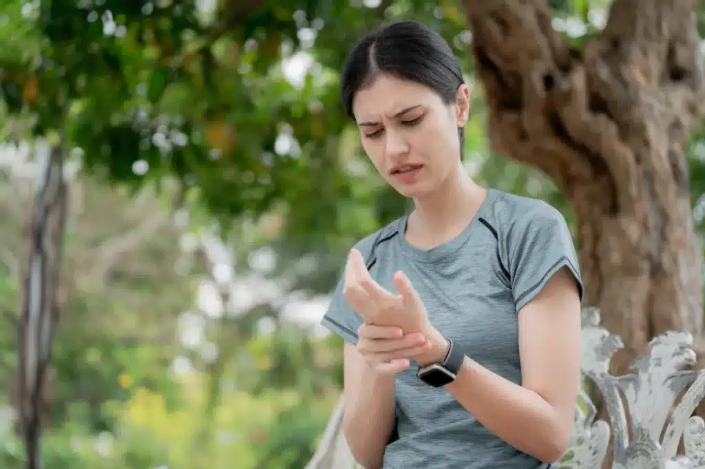 Young woman feeling numbness and tingling in fingers at the park